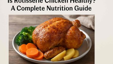 A golden-brown rotisserie chicken with crispy skin served on a plate with steamed broccoli, roasted potatoes, and carrots, set on a rustic wooden table.