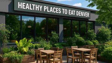 igh-resolution landscape image of a healthy restaurant in Denver with a modern exterior, large windows, wooden outdoor seating, greenery, and a “Healthy Places to Eat Denver” sign in clear daylight.